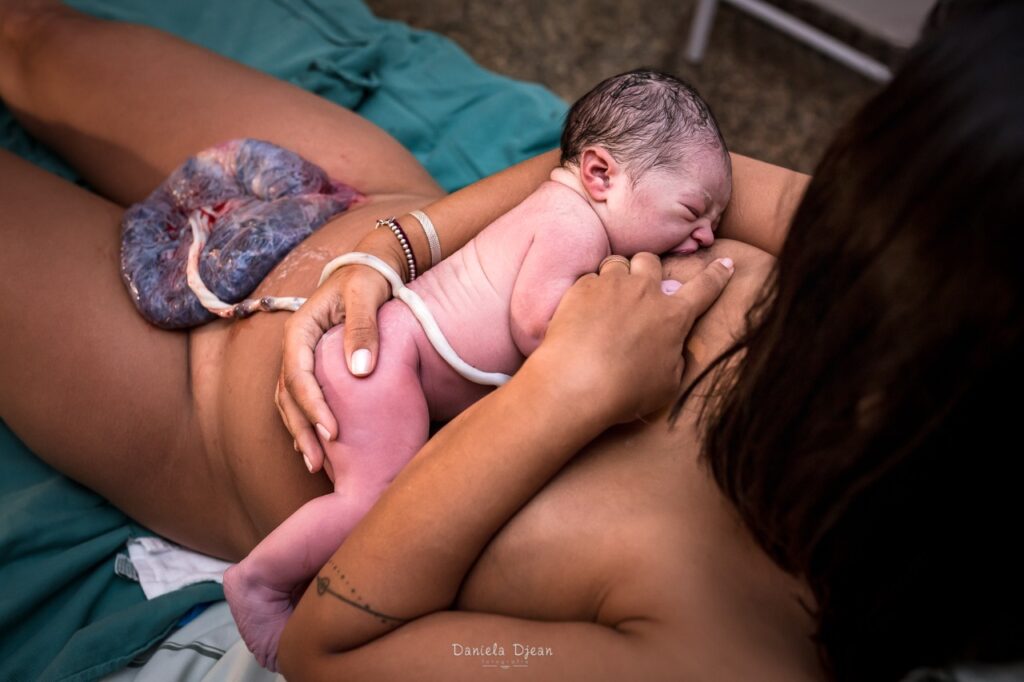 Mulher amamentando bebê recém nascido, após seu parto natural